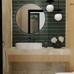 Burzyńska Studio - Nowoczesna łazienka z okrągłym lustrem, umywalką nablatową i ciemnozieloną mozaiką na ścianie, oświetlona kulistymi lampami wiszącymi, z elementami drewnopodobnymi i dyskretnym logo firmy Burzyńska...