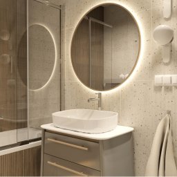 Burzyńska Studio - Nowoczesna łazienka z okrągłym lustrem z podświetleniem LED, umywalką nablatową na szafce z szufladami, prysznicem za szklaną ścianką i beżowymi płytkami z delikatnym wzorem.