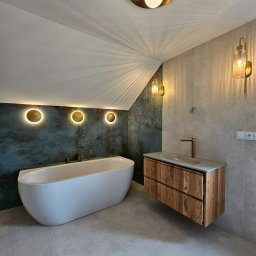 TOM LUX HOME TOMASZ HETNAR - Nowoczesna łazienka na poddaszu z wolnostojącą wanną, drewnianą szafką pod umywalką i oświetleniem punktowym. Szare płytki i akcenty złota.