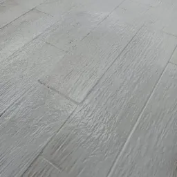 Świeżo umyta podłoga z paneli imitujących drewno, widoczne smugi wody i odbicia światła, ukośny kadr.