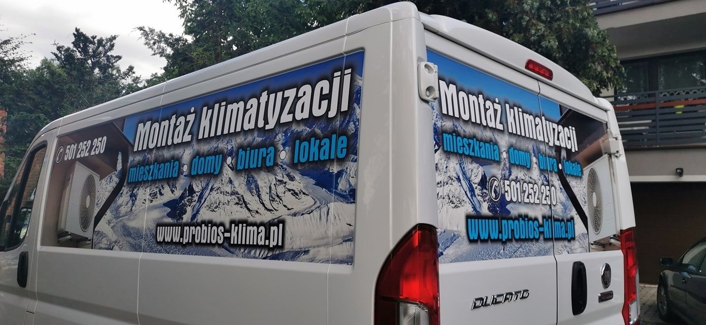 Biały samochód dostawczy z reklamą montażu klimatyzacji w Bargłówce, z widocznym numerem telefonu i adresem strony internetowej, na tle górskiego krajobrazu.