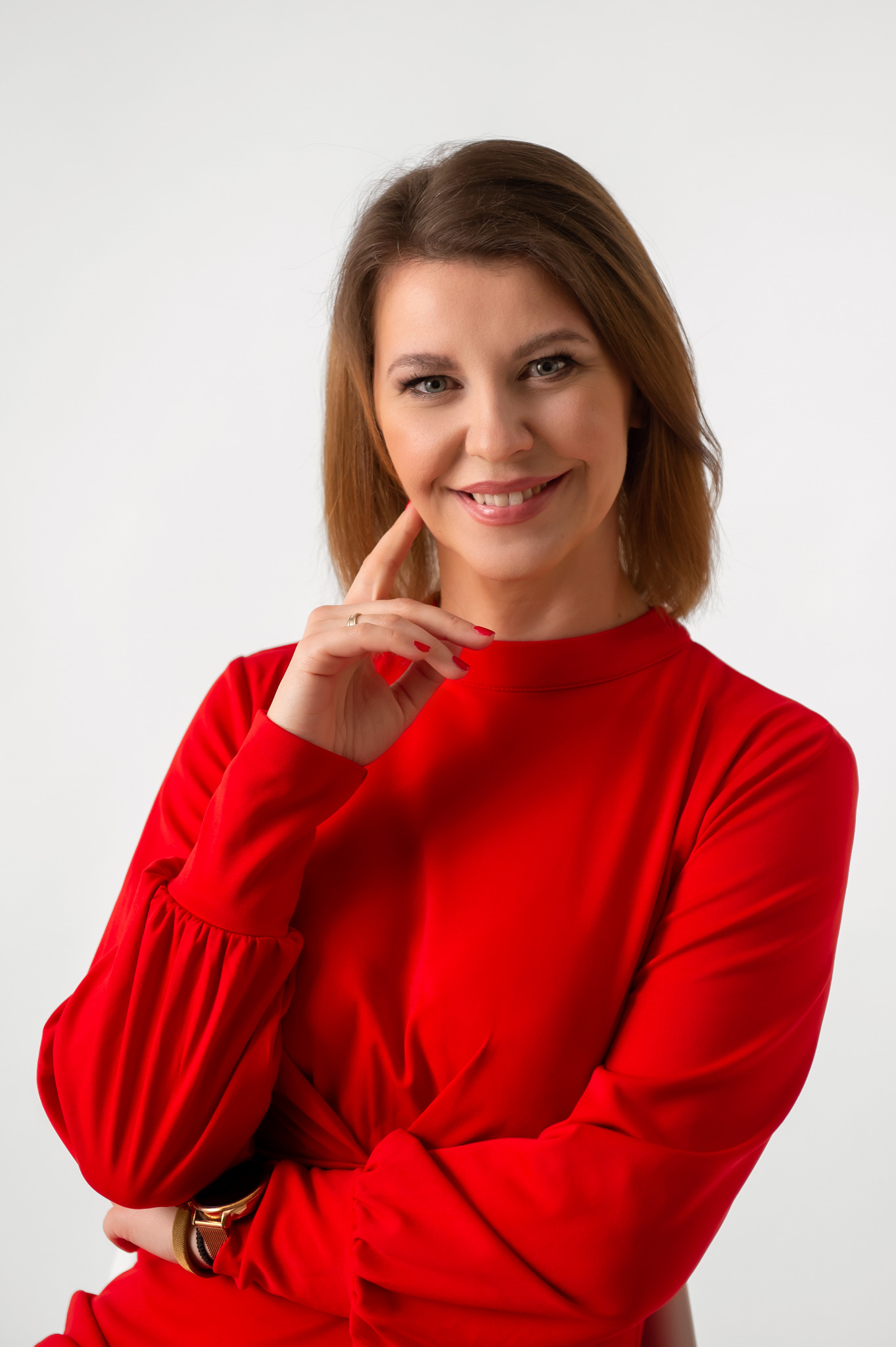 Portret uśmiechniętej kobiety w czerwonej sukience, z ręką podpartą pod brodą, prezentującej firmę z Tarnowa.