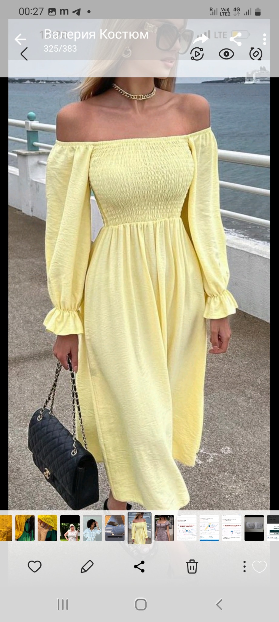 Kobieta pozuje w jasnożółtej sukience midi z odkrytymi ramionami, marszczoną górą i bufkami na rękawach, trzymając czarną pikowaną torebkę na łańcuszku, na tle morskiego krajobrazu z białą balustradą.