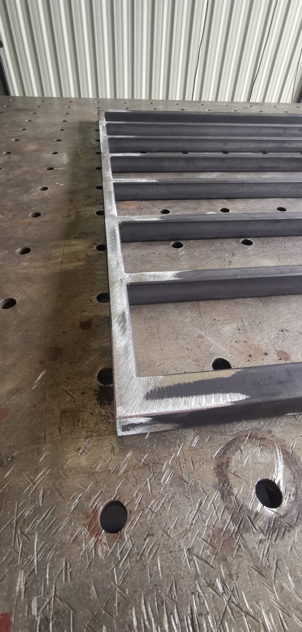 Stalowa konstrukcja kratowa z profili zamkniętych, leżąca na stole spawalniczym z otworami, widoczne ślady obróbki.