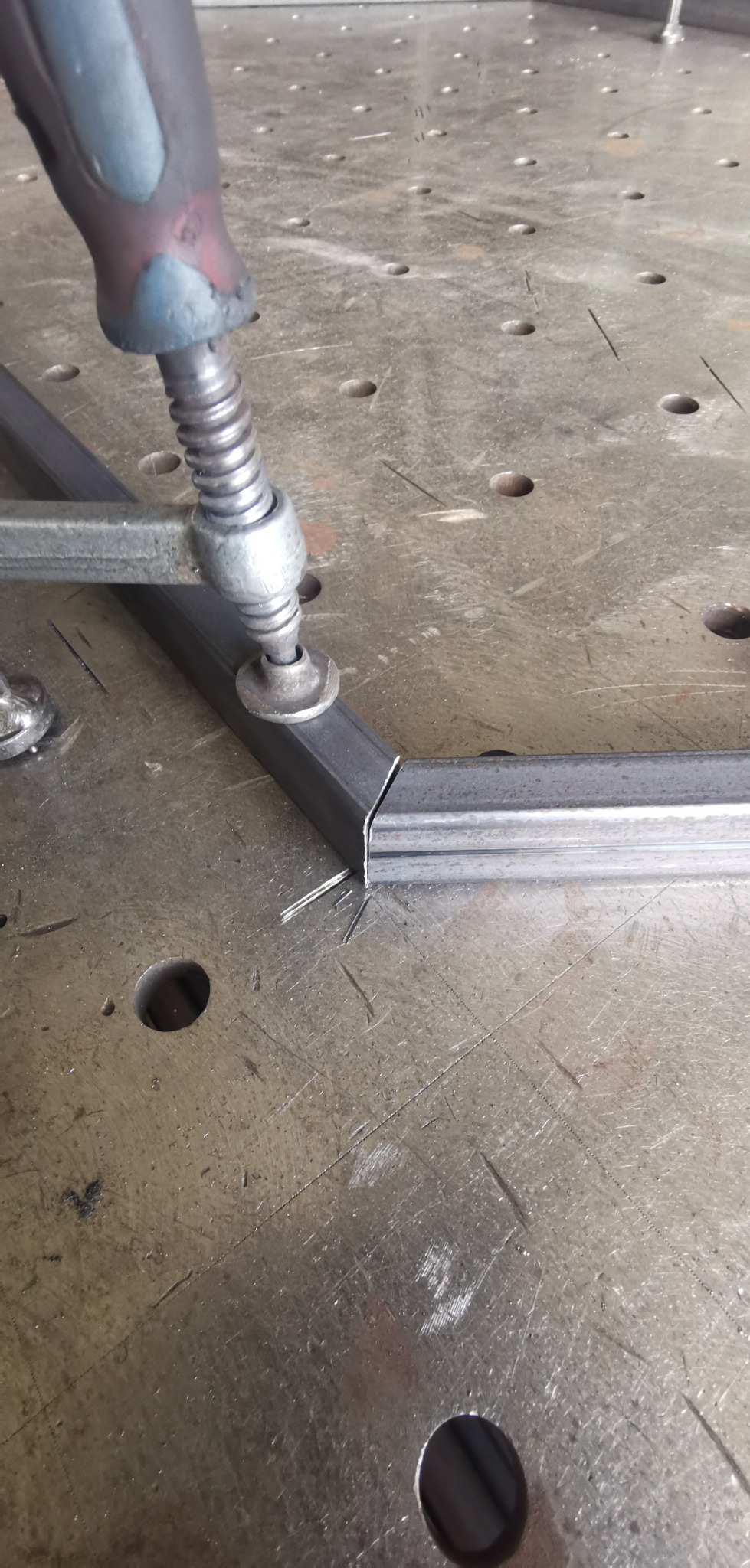 Metalowy profil zamknięty, zaciśnięty ściskiem sprężynowym na stole spawalniczym, przygotowany do spawania narożnika.