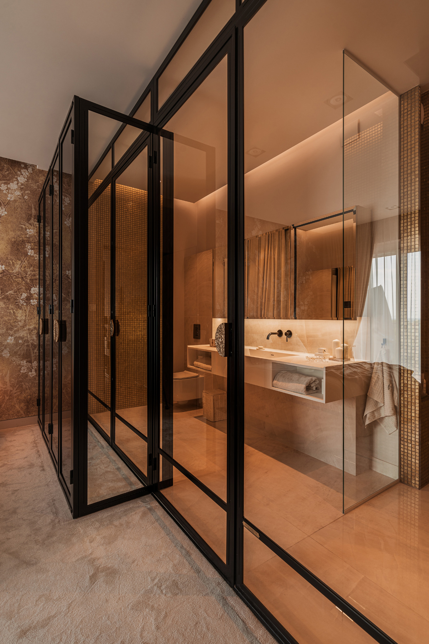 Nowoczesna łazienka z kabiną prysznicową typu walk-in, przeszkloną ścianą z czarnymi ramami, umywalką nablatową z czarną armaturą i beżowymi płytkami.