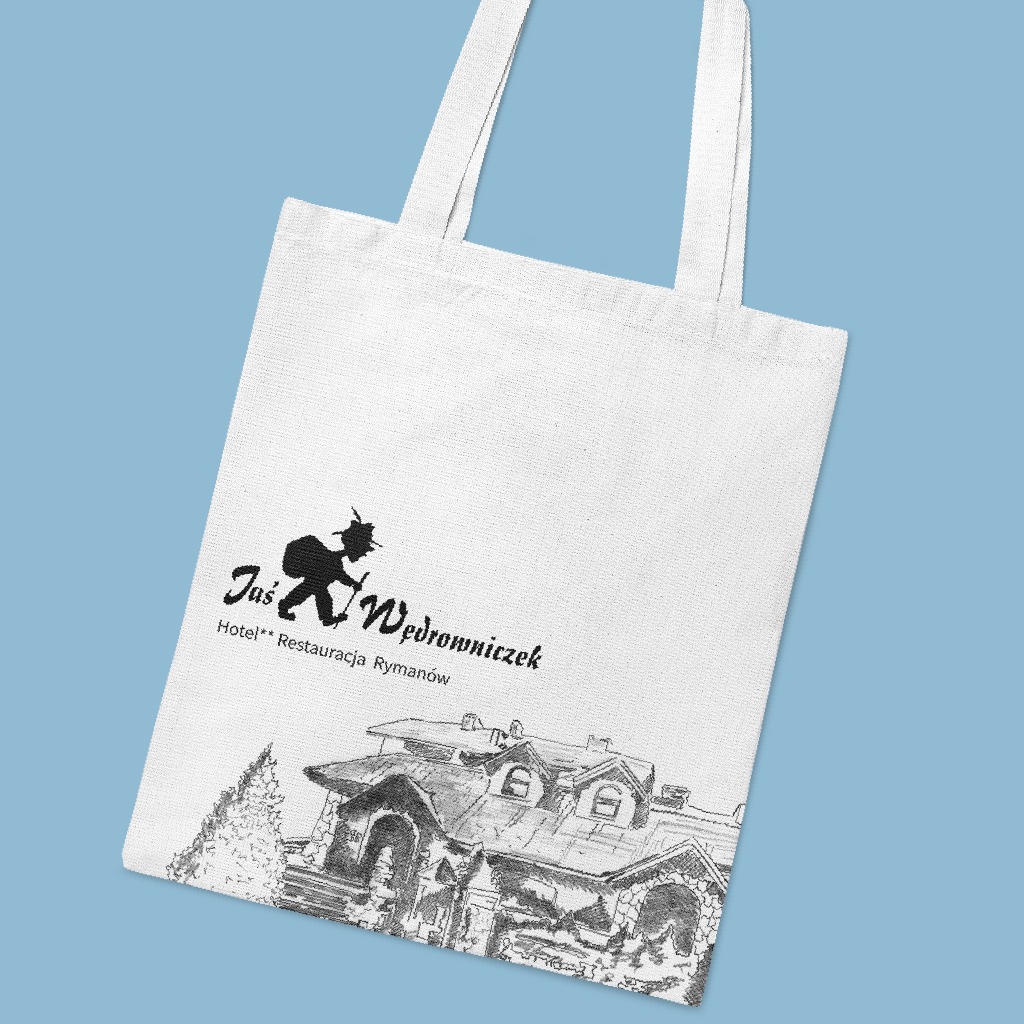 Biała torba bawełniana z czarnym nadrukiem logo hotelu i restauracji Jaś Wędrowniczek oraz szkicem budynku na błękitnym tle.