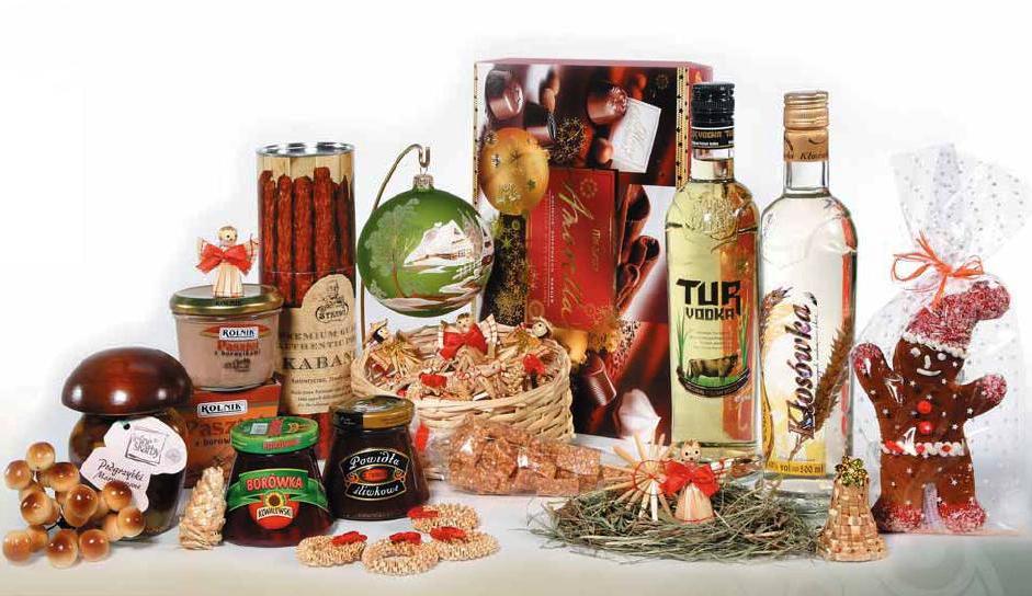 Bogato zaopatrzony kosz prezentowy z produktami spożywczymi: wódka Tur i Kłosówka, kabanosy, pasztet, powidła śliwkowe, borówka, pierniczek w folii, ozdoby świąteczne i grzyby marynowane.