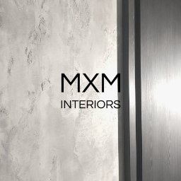Mxm Interiors - Ściana z efektem dekoracyjnym w odcieniach szarości, obok drewniane drzwi z nowoczesną klamką, widoczne logo MXM Interiors.
