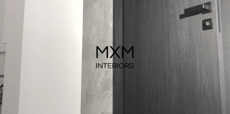 Nowoczesne, grafitowe drzwi wewnętrzne z metalową klamką, na tle białej ściany i ściany z efektem betonu architektonicznego, z widocznym logo MXM Interiors.