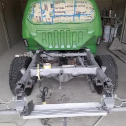 Karoseria samochodu typu pick-up po lakierowaniu na zielono, z zabezpieczonymi gazetami szybami, widoczna rama po konserwacji w warsztacie w Jabłonowie Pomorskim.