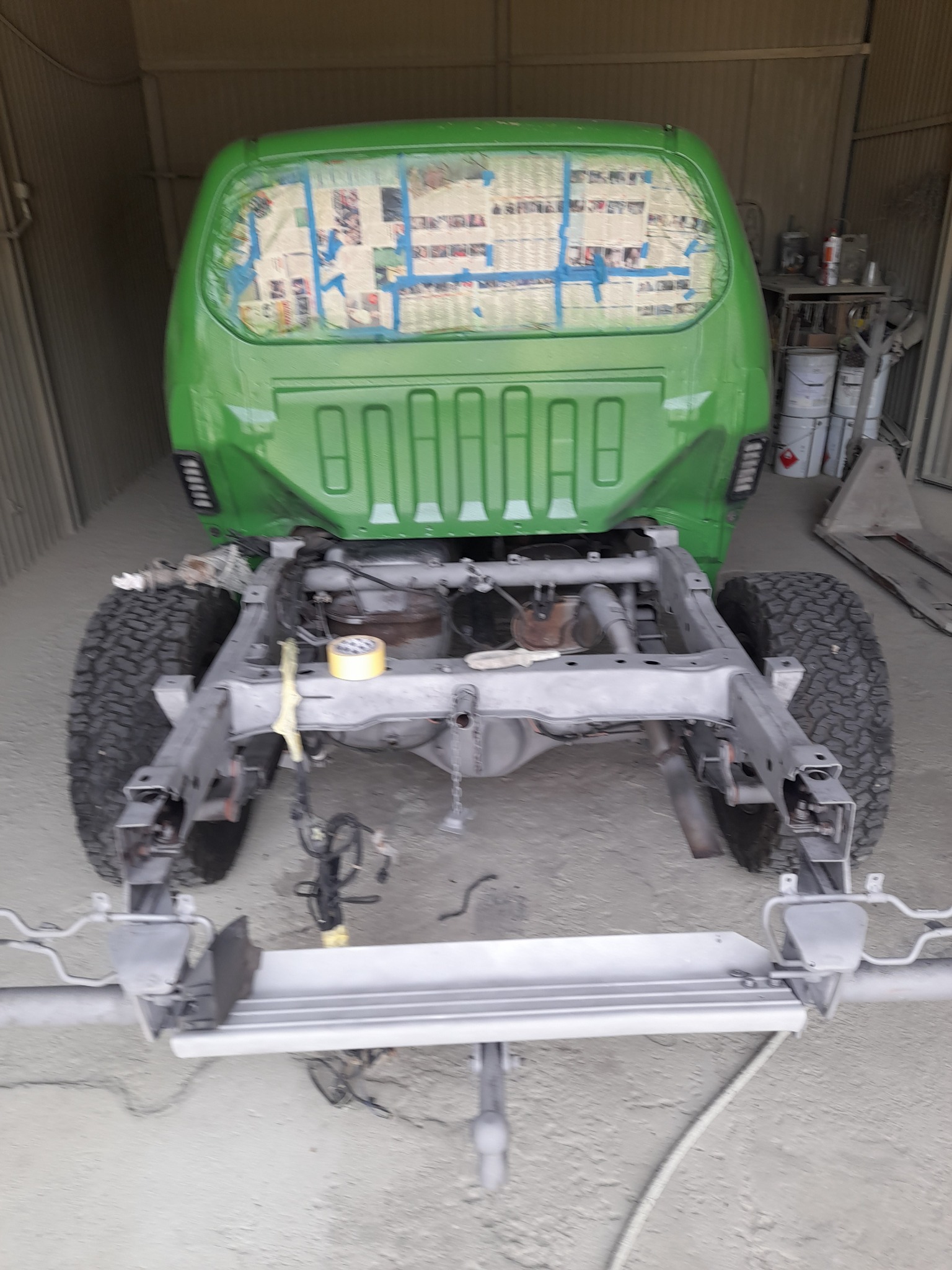 Karoseria samochodu typu pick-up po lakierowaniu na zielono, z zabezpieczonymi gazetami szybami, widoczna rama po konserwacji w warsztacie w Jabłonowie Pomorskim.