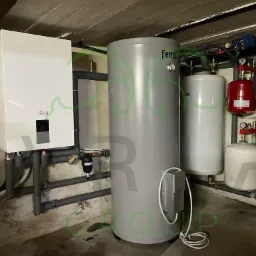 Kompletna instalacja grzewcza marki Ferroli w piwnicy, widoczne: piec gazowy, zbiornik buforowy, naczynia wzbiorcze i rury instalacyjne.