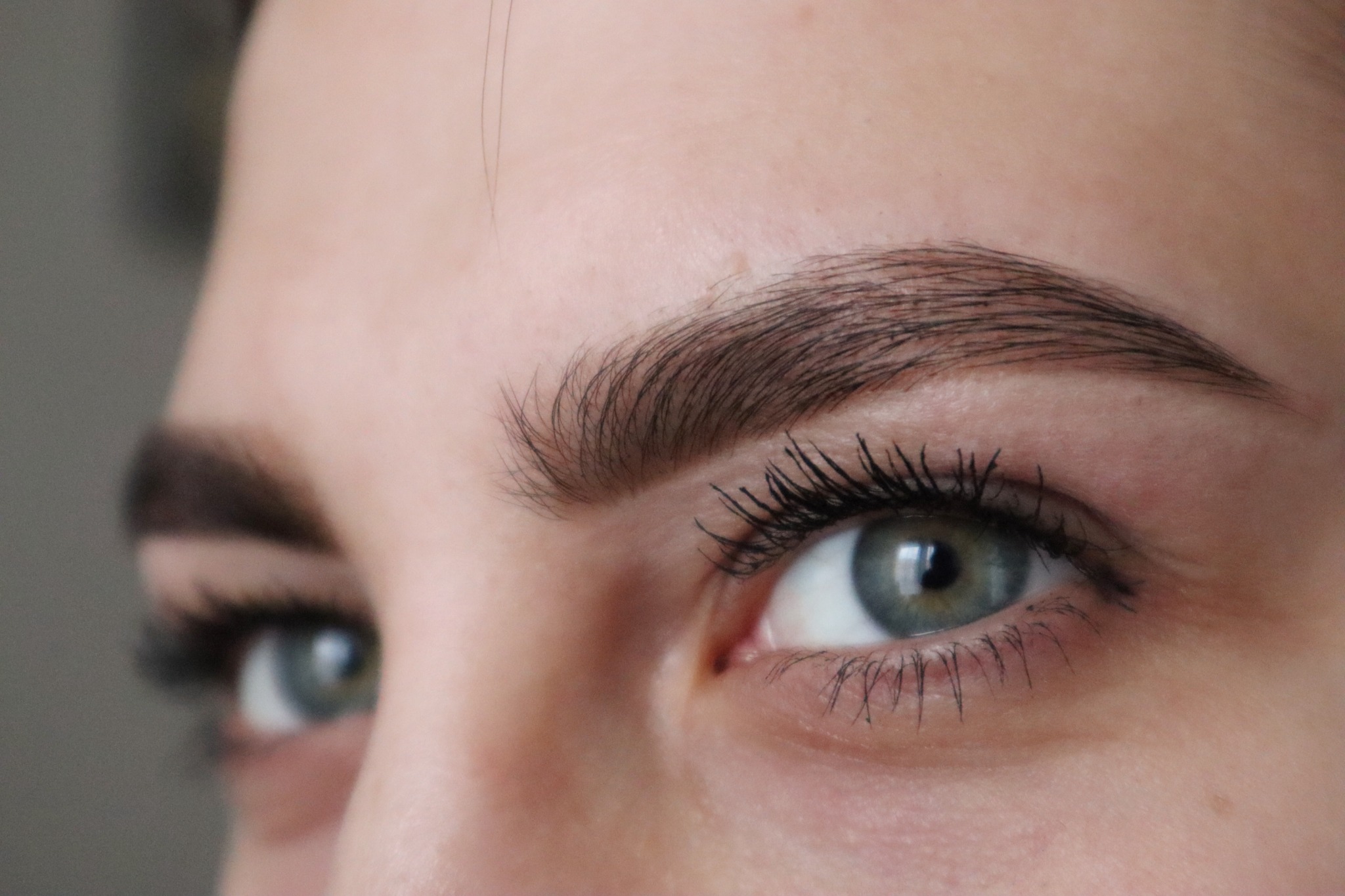Zbliżenie na oko z podkreślonymi rzęsami tuszem i wyregulowanymi brwiami o naturalnym wyglądzie.