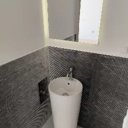 Biała, wolnostojąca umywalka z chromowaną baterią na tle ściany wyłożonej czarno-białymi płytkami w paski, oświetlone lustro z wbudowanym światłem LED.