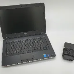Otwarty laptop Dell Latitude E6440 z czarną klawiaturą i touchpadem, obok zwinięty zasilacz na białym tle.