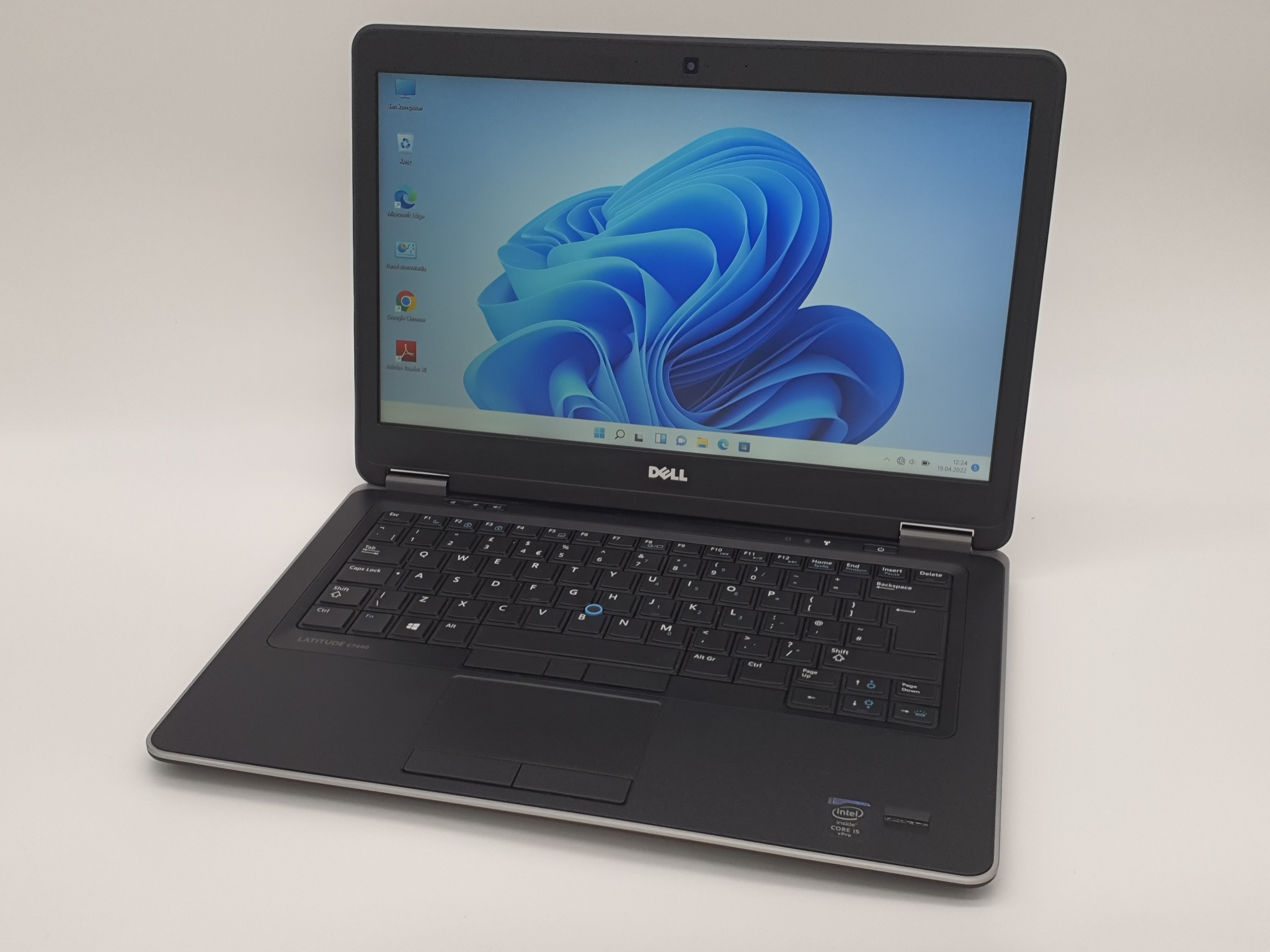 Otwarty laptop Dell Latitude E7440 na białym tle, ekran wyświetla domyślną tapetę Windows 11, widoczna klawiatura i touchpad, naklejka Intel Core i5 vPro na obudowie.