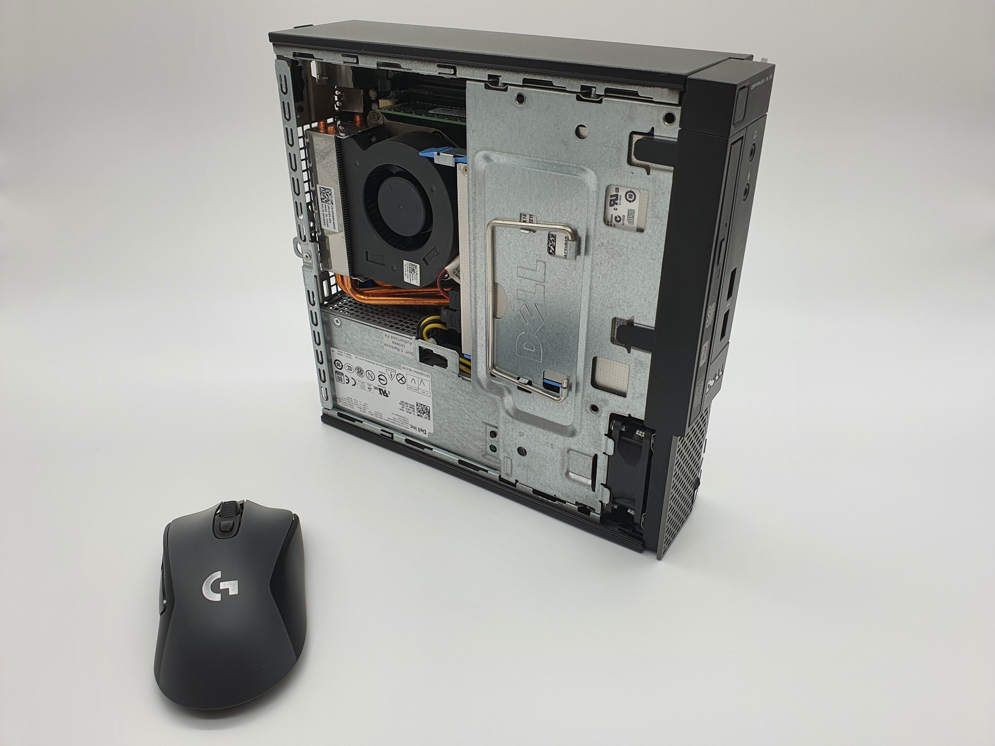 Otwarta obudowa komputera stacjonarnego Dell OptiPlex z widocznym wnętrzem i elementami chłodzenia, obok czarna myszka bezprzewodowa Logitech.