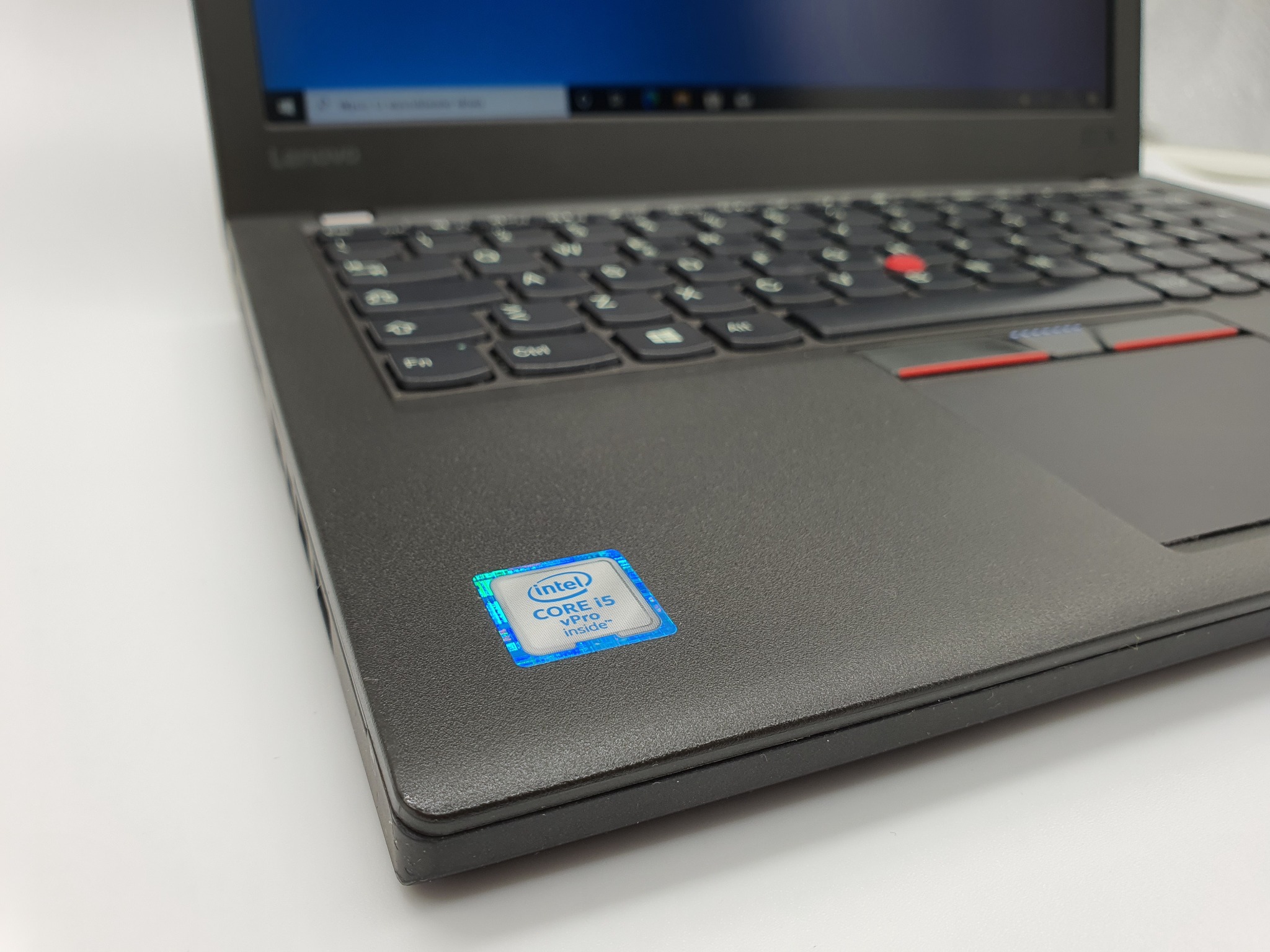 Ciemnoszary laptop Lenovo ThinkPad z naklejką Intel Core i5 vPro, widoczna klawiatura i touchpad z czerwonymi akcentami.