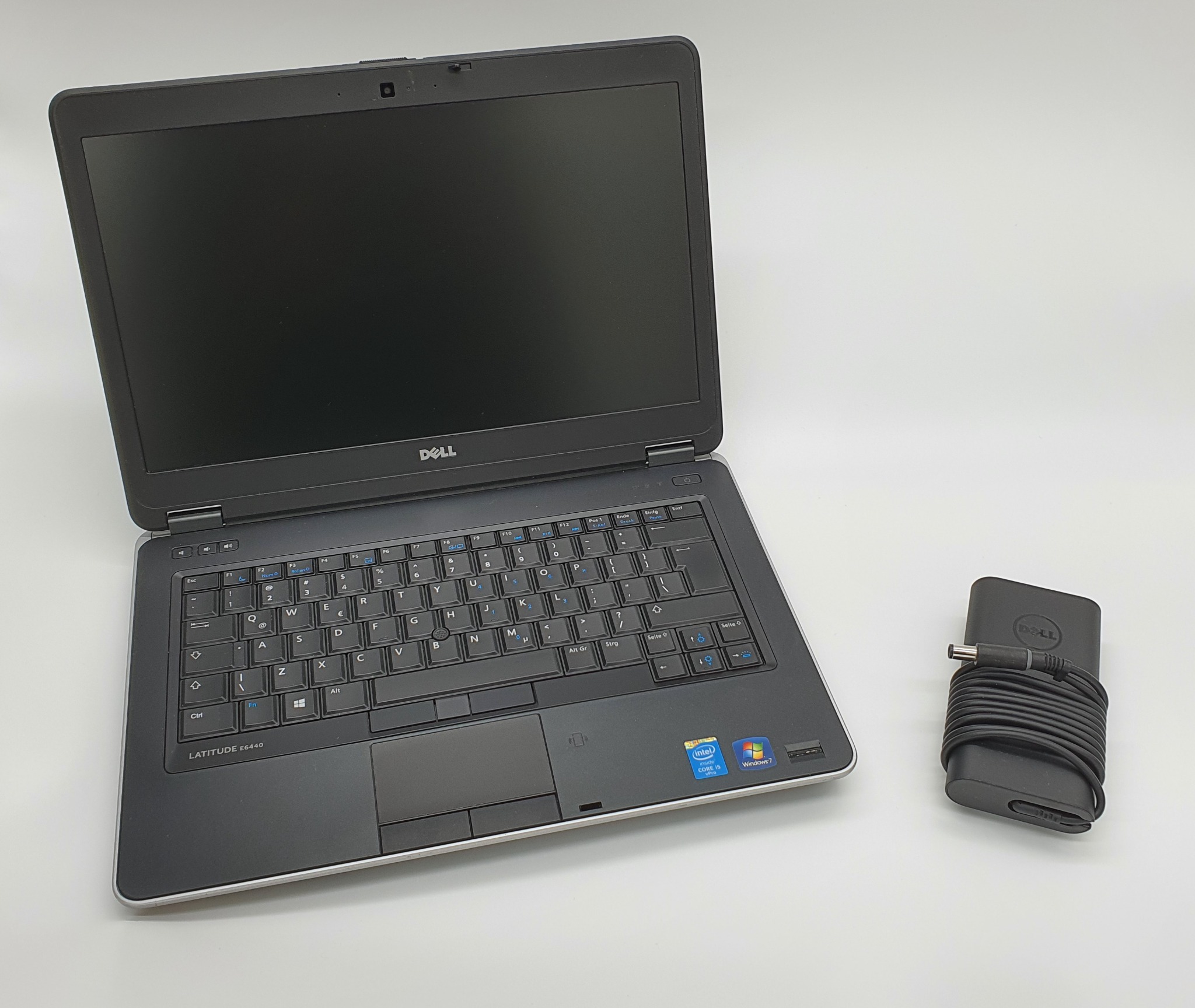 Otwarty laptop Dell Latitude E6440 z czarną klawiaturą i touchpadem, obok zwinięty zasilacz na białym tle.
