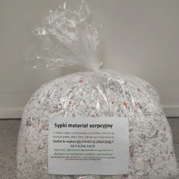 Worek foliowy wypełniony sypkim materiałem sorpcyjnym z fragmentami pomarańczowych elementów, przeznaczonym do pochłaniania substancji ropopochodnych i olejów, z etykietą informacyjną na froncie.