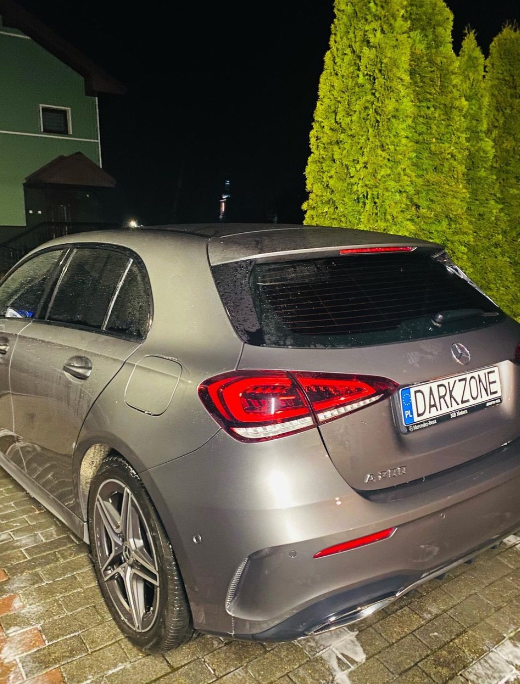 Szary Mercedes A-klasa z przyciemnionymi tylnymi szybami, zaparkowany na zewnątrz w nocy, widoczne tylne światła i tablica rejestracyjna z napisem DARKZONE.