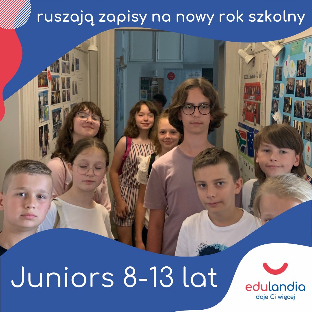 Grupa uśmiechniętych dzieci w wieku 8-13 lat stojąca w korytarzu przed tablicą z materiałami edukacyjnymi, promująca zapisy na nowy rok szkolny w Edulandii.