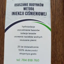 Biała ulotka reklamowa na drewnianym tle, oferująca osuszanie budynków metodą iniekcji ciśnieniowej, hydroizolacje, uszczelnianie basenów, izolacje tarasów, usuwanie nacieków wodnych i osuszanie...