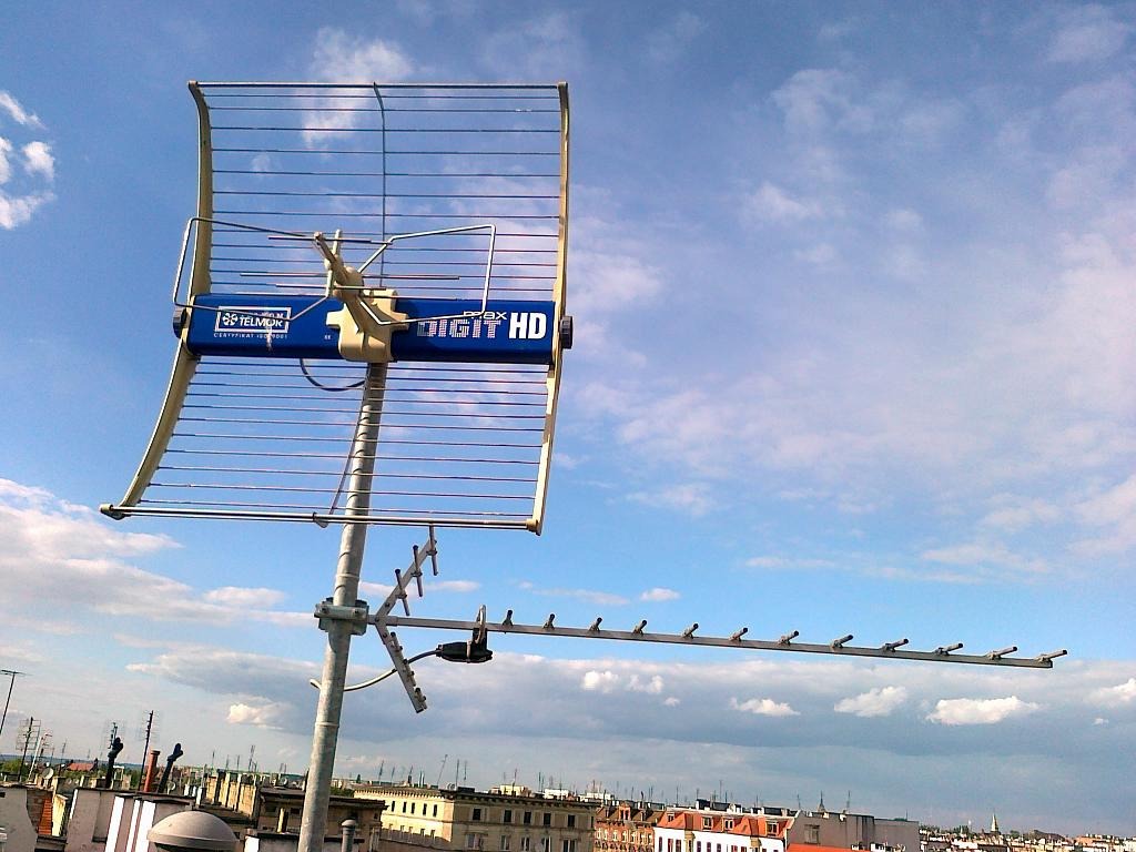 Antena Telmor Digit HD zamontowana na dachu budynku we Wrocławiu, widok z góry na miasto i błękitne niebo z chmurami.