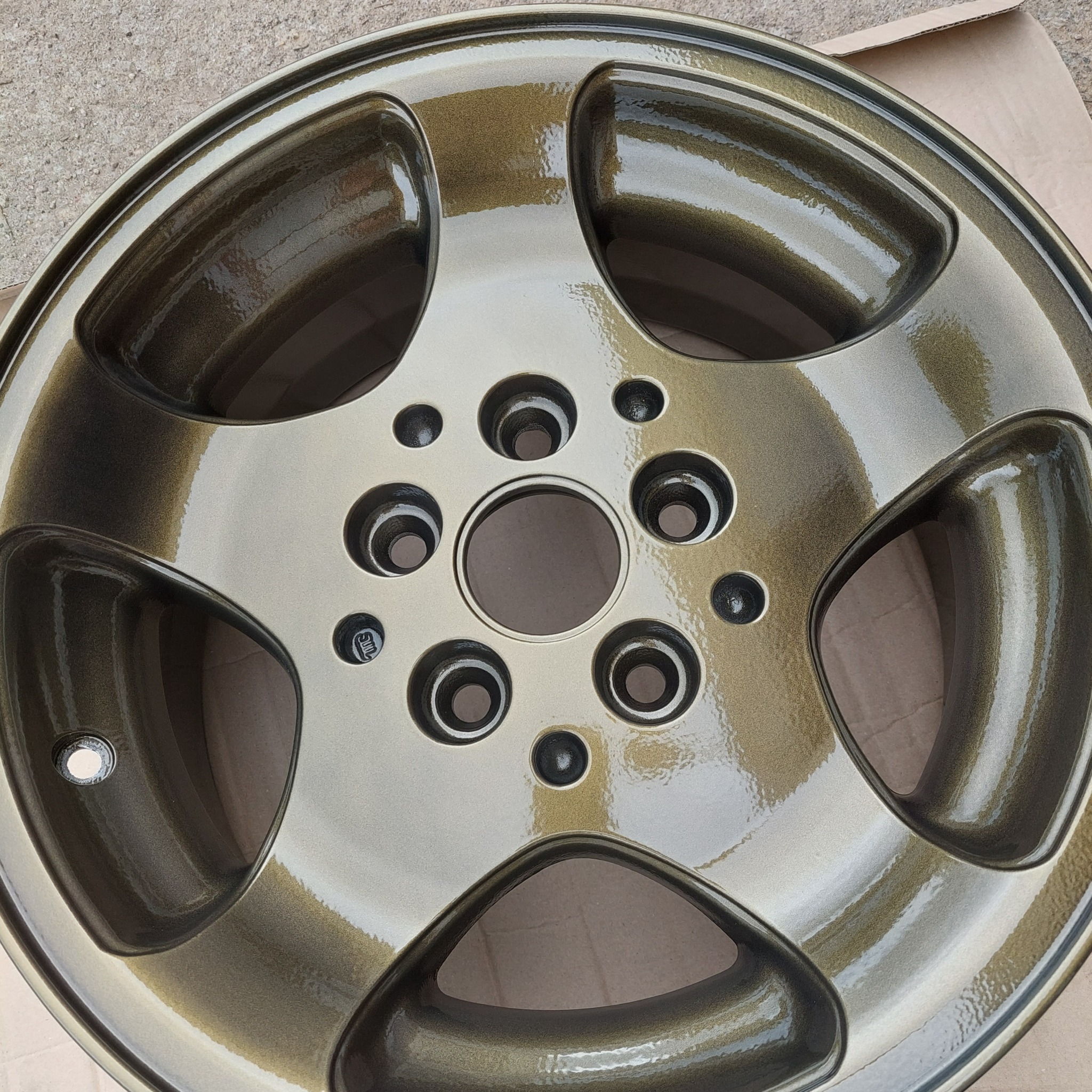 Odnowiona felga aluminiowa w odcieniach złota i brązu, z widocznymi refleksami światła na gładkiej powierzchni