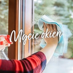 Kamila Marzec - Osoba w koszuli w kratę czyści okno za pomocą spryskiwacza i niebieskiej ściereczki z mikrofibry, widoczne krople wody na szybie.