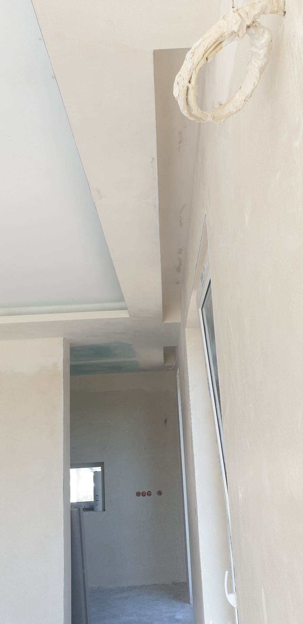 Sufit podwieszany z płyt karton-gips, widoczne łączenia wymagające szpachlowania, surowy stan wykończenia wnętrza z widocznymi instalacjami elektrycznymi.