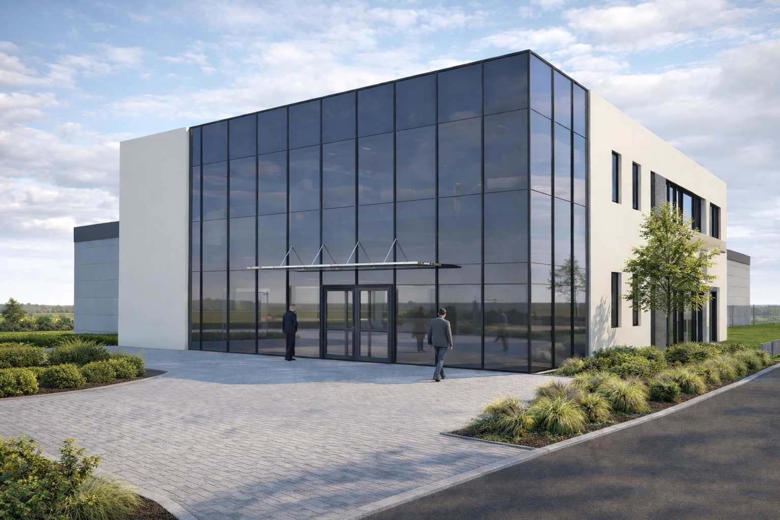 Nowoczesny budynek biurowy z przeszkloną fasadą i dwoma osobami w pobliżu wejścia, otoczony zielenią i brukowanym podjazdem w słoneczny dzień.