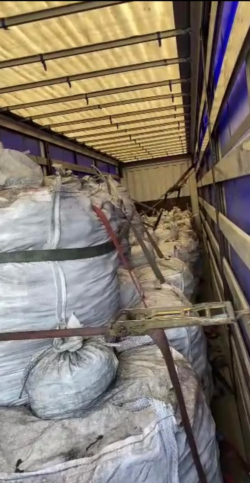 Wnętrze naczepy wypełnionej workami z opałem, zabezpieczonymi pasami transportowymi.