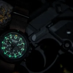 Zdjęcie reklamowe zegarka Traser z podświetlaną tarczą na tle pistoletu Beretta 92, wykonane w Gliwicach.