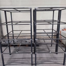 BAJ-DESIGN Błażej Dostatni - Dwie surowe, metalowe konstrukcje szkieletowe z profili, spawane, bez obróbki wykończeniowej, w hali produkcyjnej, z widocznymi śladami spawania.