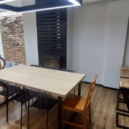 Nowoczesne biuro w Wirach z dużym stołem konferencyjnym, czarnymi krzesłami i rowerem opartym o ścianę z betonowych płyt.