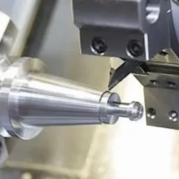 Obróbka metalu na tokarce CNC: precyzyjne toczenie stożkowego elementu z metalu, widoczne narzędzie skrawające w trakcie pracy.