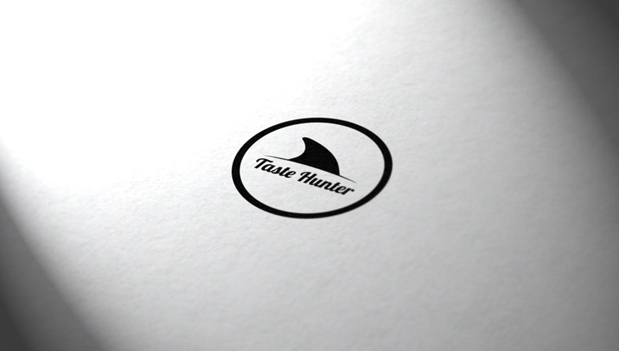 Czarno-białe logo firmy Taste Hunter z motywem płetwy rekina w okręgu, umieszczone na teksturowanym, białym tle z delikatnym cieniem.