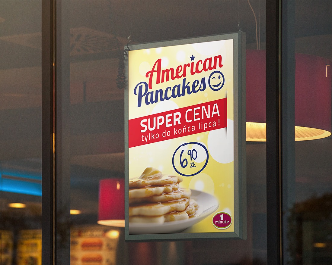 Podświetlany plakat reklamowy 'American Pancakes' z super ceną, wiszący w witrynie we Wrocławiu, widoczny z zewnątrz, z odbiciami wnętrza lokalu w szkle.