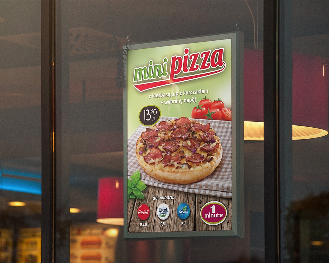Plakat reklamowy mini pizzy z kiełbasą i napojem, wiszący w oknie lokalu, widoczne logo Coca-Coli, Kropli Beskidu i Nestea.