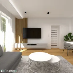 Wizualizacja salonu w jasnych barwach z drewnianymi lamelami na ścianie, białym stolikiem kawowym i szarą sofą, widok na okno z firanką.