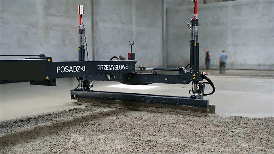 Maszyna do wylewania posadzek przemysłowych w trakcie pracy, z widocznymi laserowymi czujnikami poziomowania i dwoma pracownikami w tle.