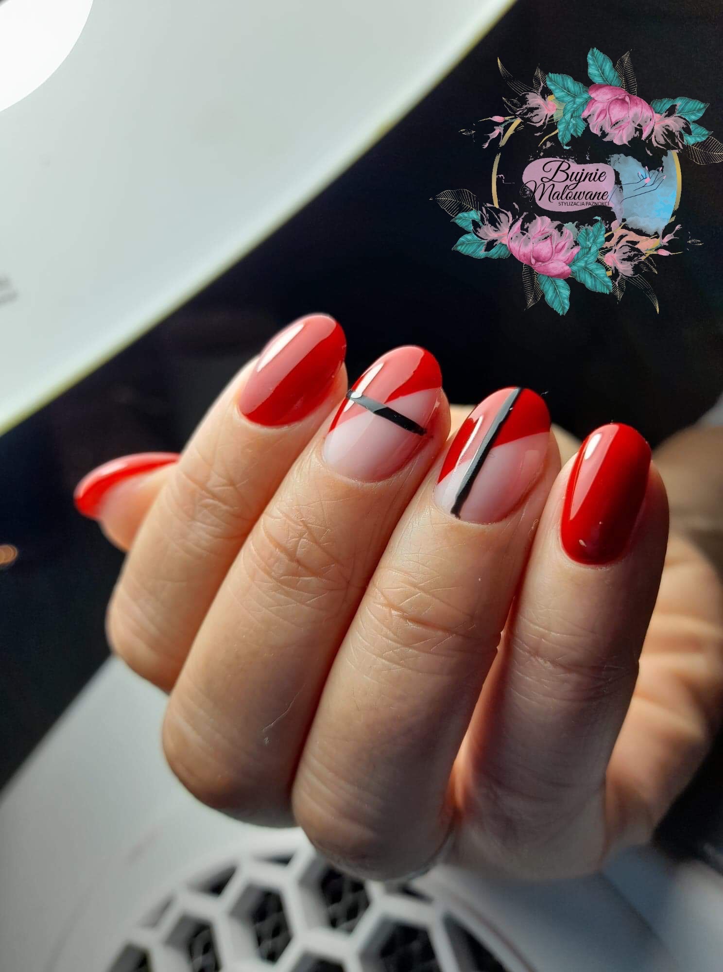 Czerwone paznokcie z geometrycznym wzorem: czerwono-białe z czarnymi paskami, na tle logo salonu stylizacji paznokci.