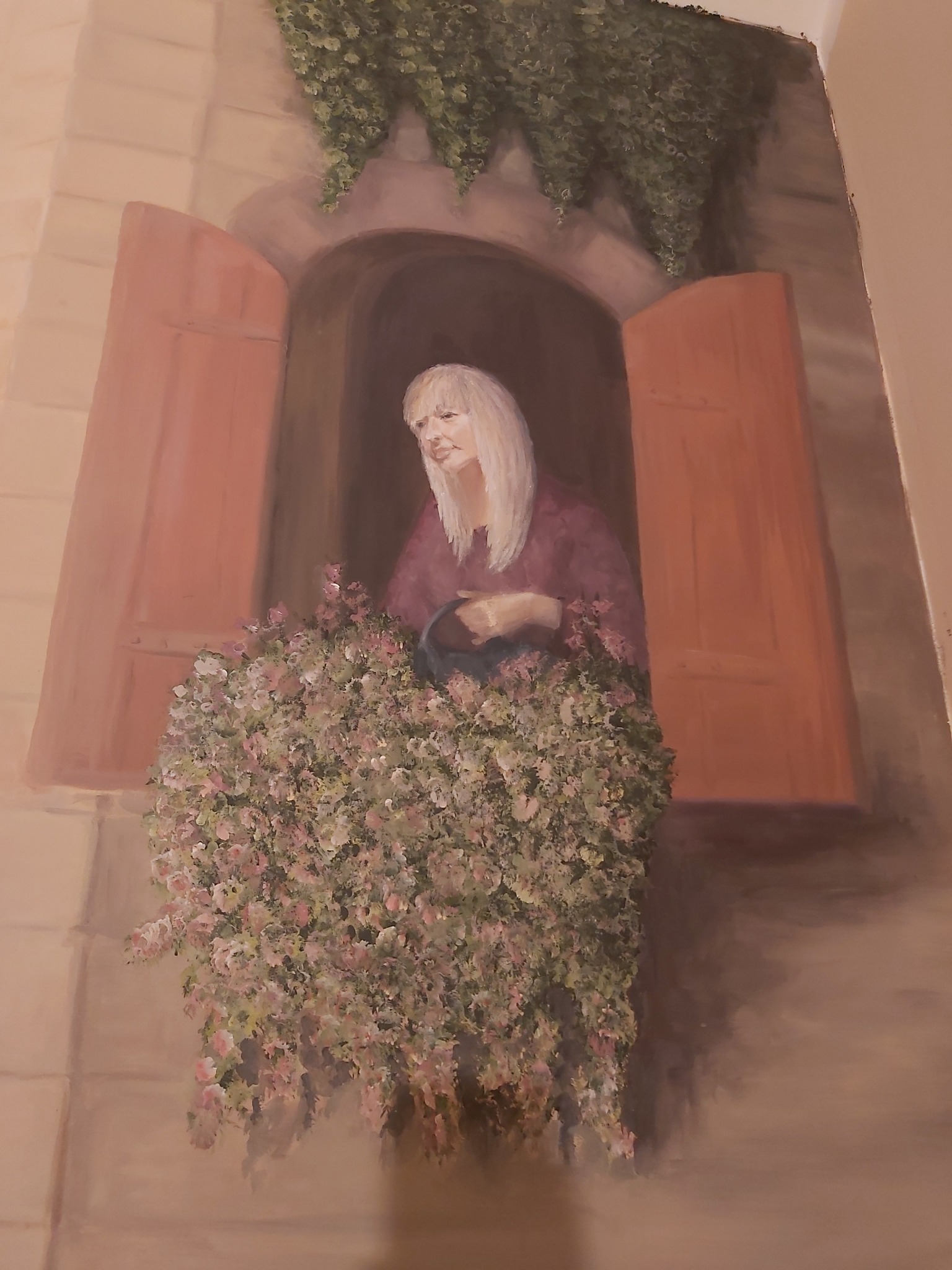 Iluzjonistyczne malowidło ścienne przedstawiające kobietę w oknie z kwiatami, stylizowane na renesansowe.