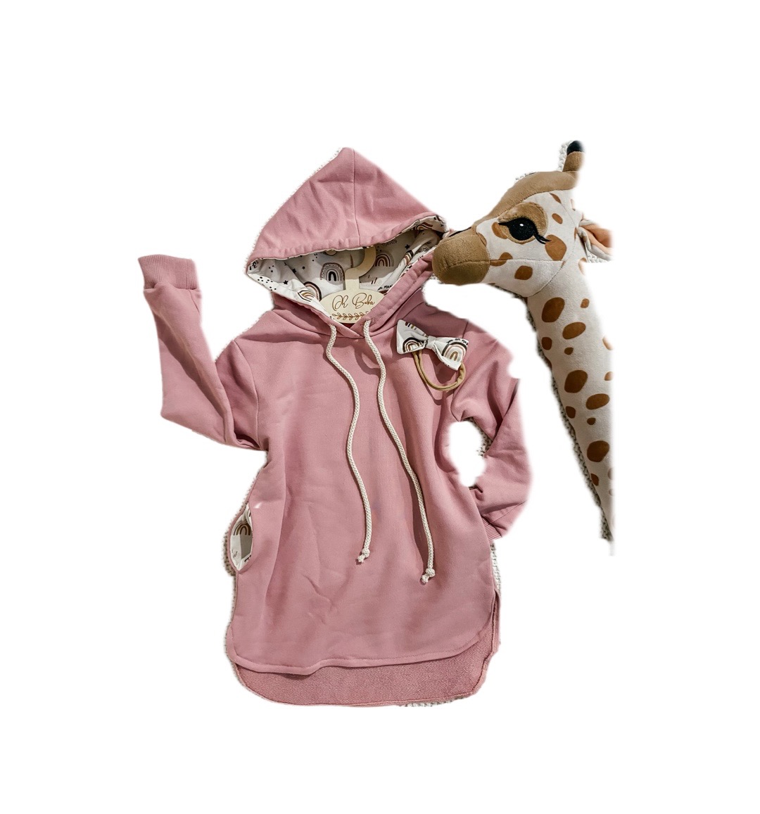 Różowa bluza dresowa z kapturem i sznurkami, z dekoracyjną kokardką z motywem tęczy, prezentowana obok pluszowej żyrafy na białym tle.