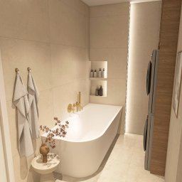 Pro Invest Black&White Aranżacja Wnętrz - Nowoczesna łazienka w beżowej tonacji z wolnostojącą wanną, złotą armaturą i dekoracyjnym bukietem na stoliku. Minimalistyczny design z wnękami na kosmetyki i pralką w zabudowie.