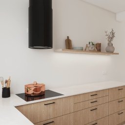 Pro Invest Black&White Aranżacja Wnętrz - Jasna kuchnia z drewnianymi szafkami, czarnym okapem i miedzianym garnkiem na płycie. Półka z dekoracjami podświetlona LED. Minimalistyczny design.