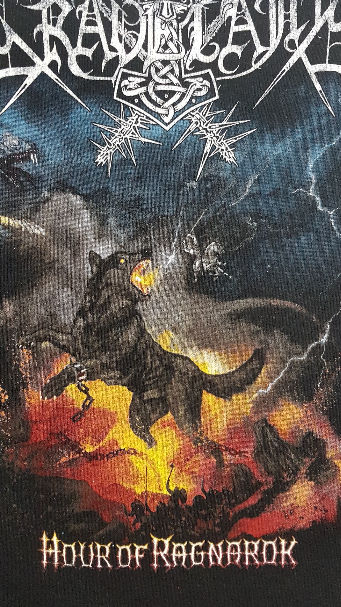 Czarna koszulka z nadrukiem w stylu metalowym przedstawiającym wilka ziejącego ogniem, łańcuchy, błyskawice i napis 'Hour of Ragnarok'.