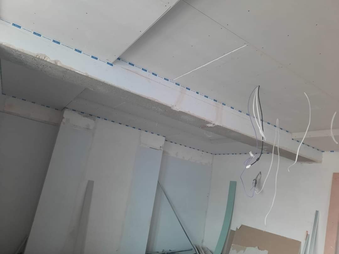 Wnętrze w trakcie prac wykończeniowych: sufit podwieszany z płyt gipsowo-kartonowych, widoczne kable elektryczne i profile montażowe.